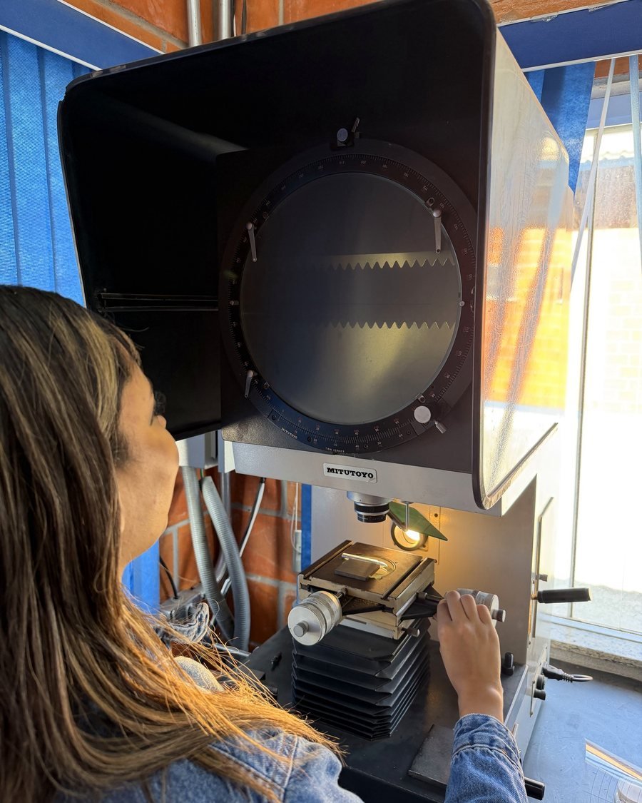 Técnica inspecionando uma peça no projetor de perfil